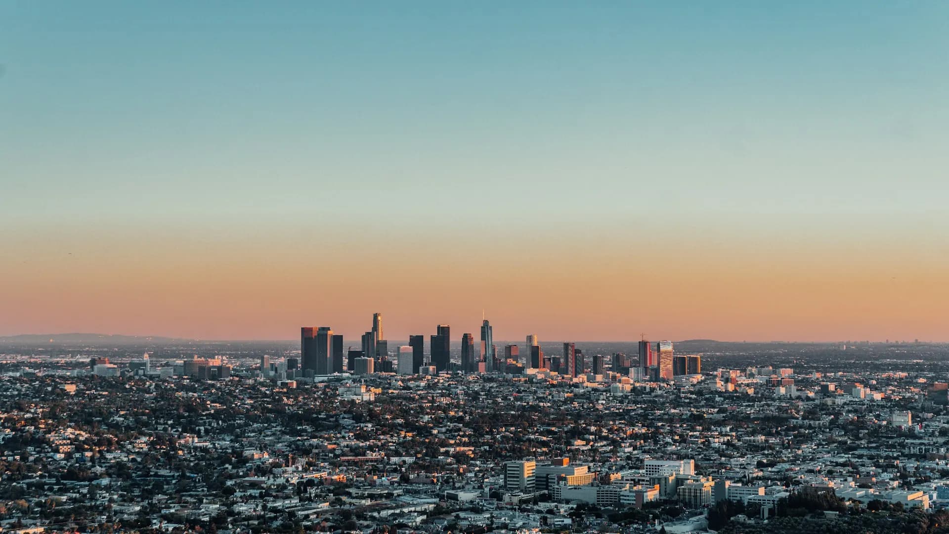 A high-angle aerial view looking across the vast urban landscape of the Los Angeles basin towards the central downtown skyline, showcasing the location of Skilled Nursing Facilities in the LA metro area.