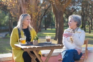 Two older women sitting at the park while having a conversation